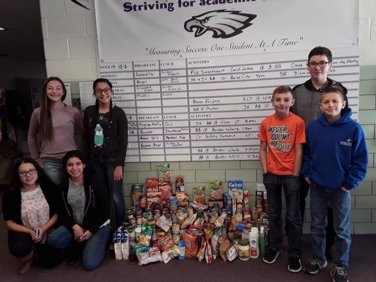Kids standing in front of collected food for food drive